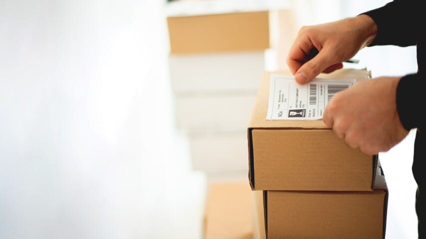 Person putting a shipping label on a box.