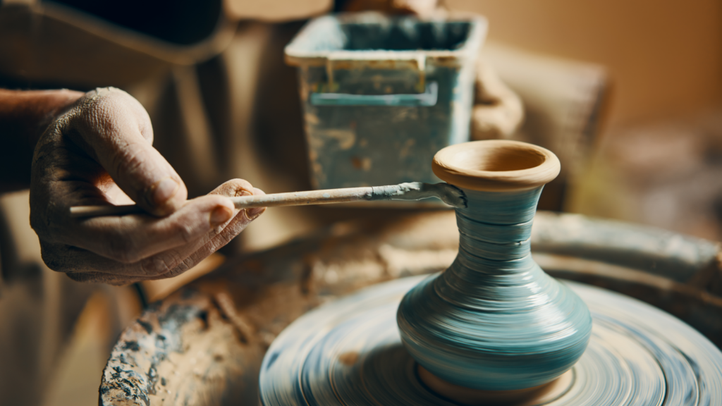 A person coloring handmade pottery.