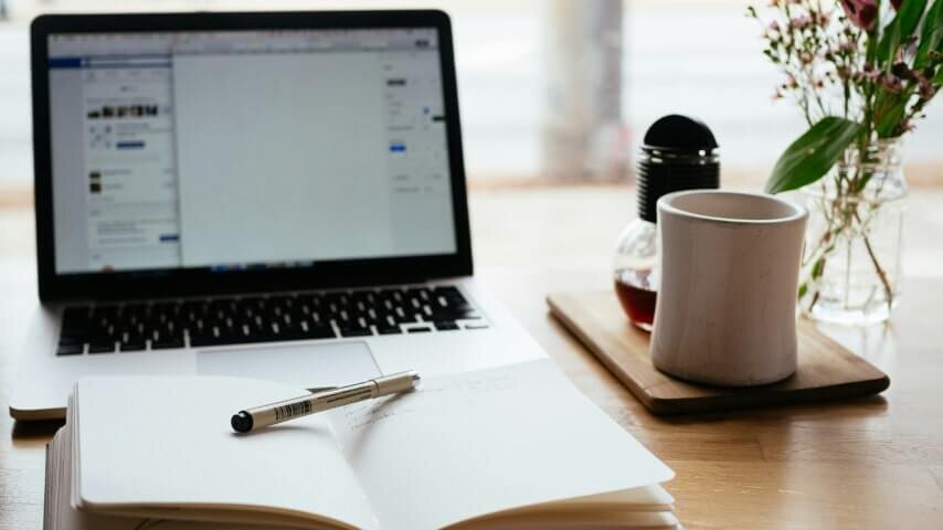 An open notebook in front of a laptop.
