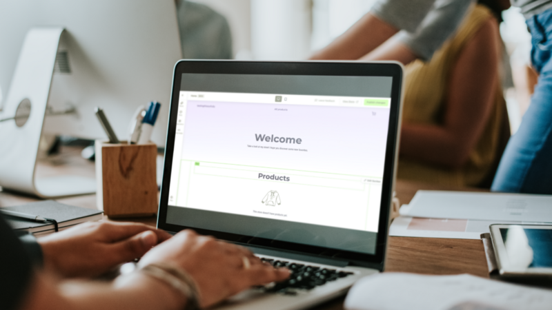 A person is using a laptop with Printify’s Pop-Up Store editor on the screen, creating an online store.