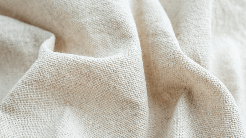 A light-colored linen fabric, slightly folded.