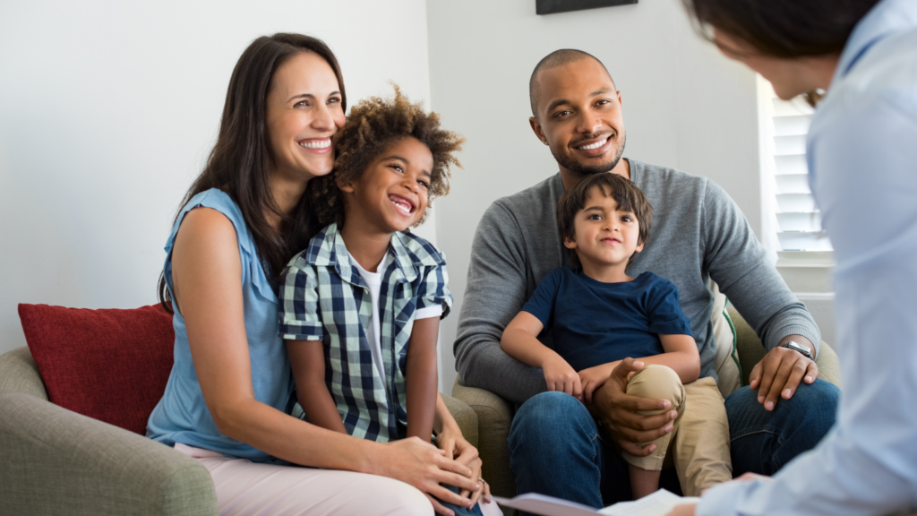 A family and a teacher seated on a couch engaged in a discussion about parenting.