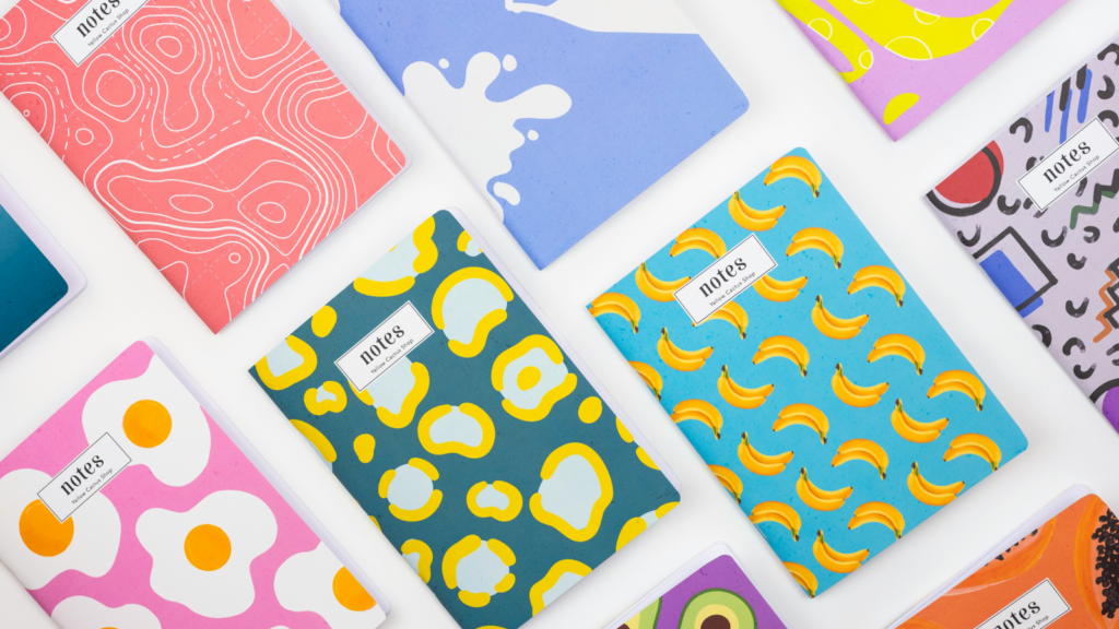 A vibrant assortment of notebooks featuring various colorful designs arranged together on a flat surface.