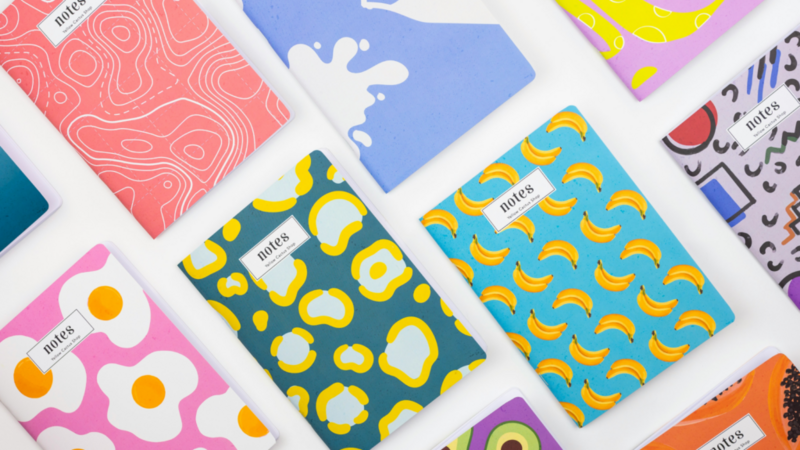 A vibrant assortment of notebooks featuring various colorful designs arranged together on a flat surface.