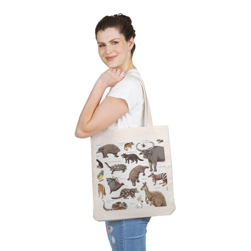 Woman carrying a tote bag with a design of various Australian animals and their names.