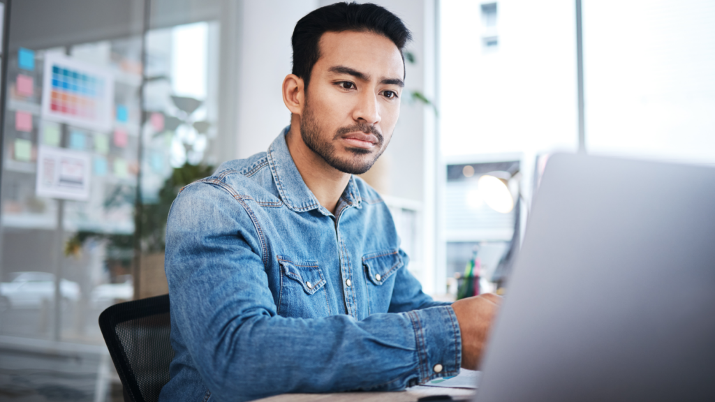 A man looking at a laptop screen and thinking.