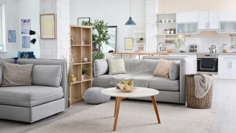 A cozy living room featuring a couch, coffee table, and an open kitchen area in the background.