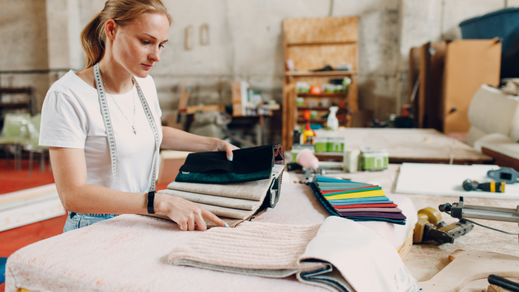 A woman looks at different fabric types in a well-organized sewing room.