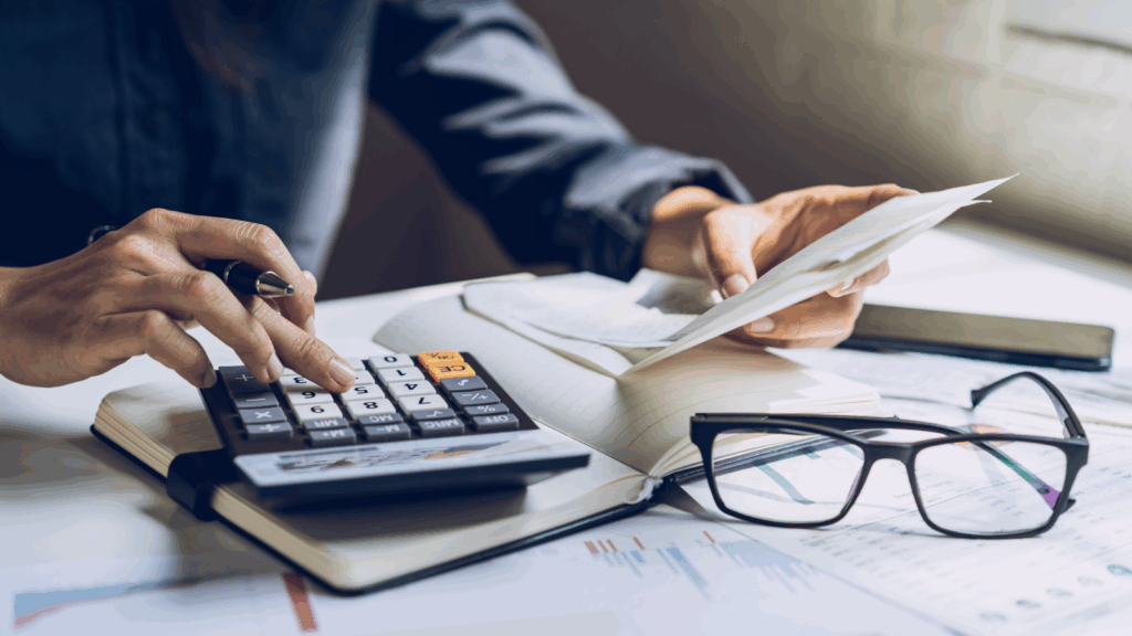 Businesswoman calculating taxes with a calculator, focused on her work in a professional office setting.