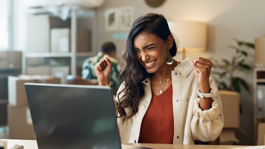 A happy woman looking at a laptop screen.