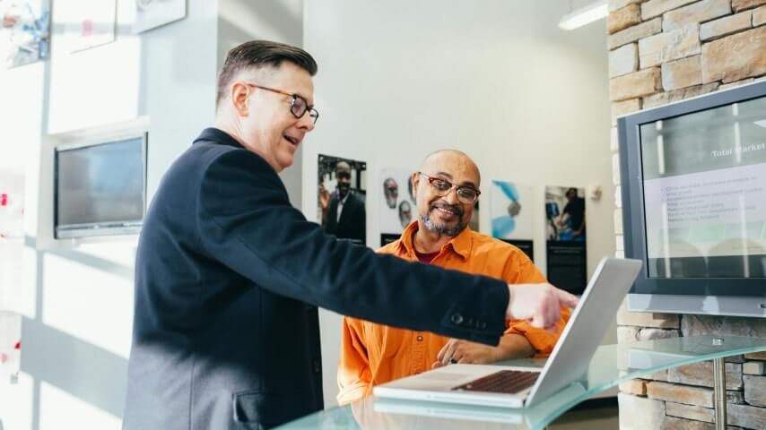 Two men looking at a laptop screen in an office.
