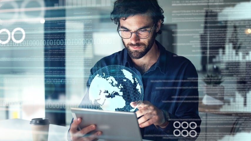 A man looking at his tablet, from which a digital graphic of the globe is emerging.