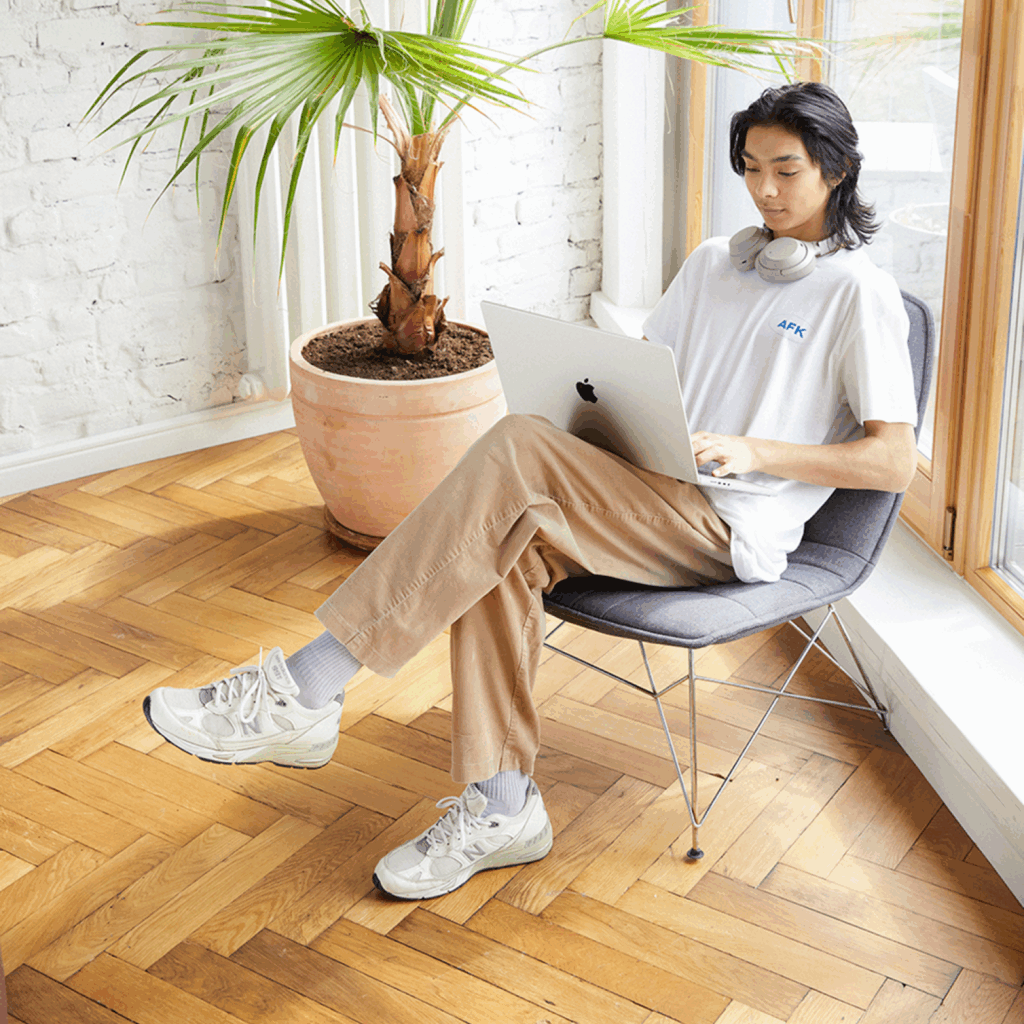 A young man is sitting on a chair, using a laptop to find out how to make money online for beginners.