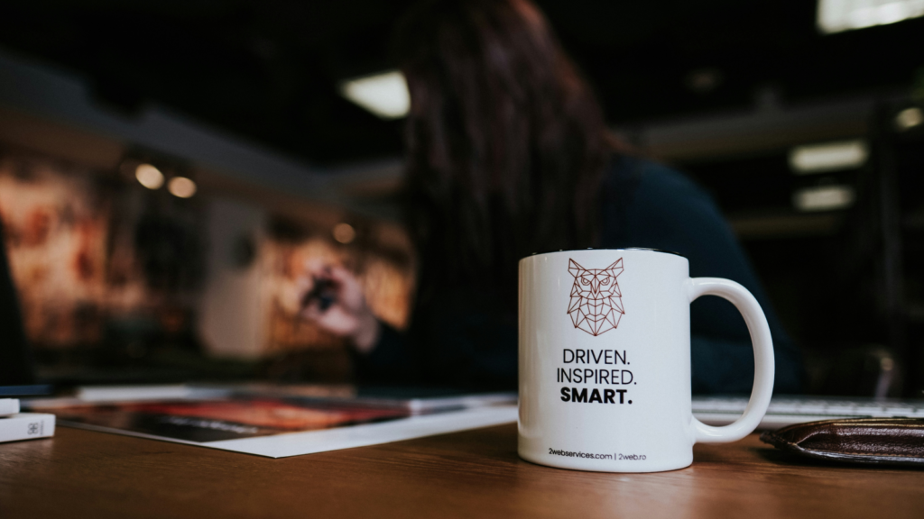 A woman seated at a desk, focused on her work, with a coffee mug placed in front of her.