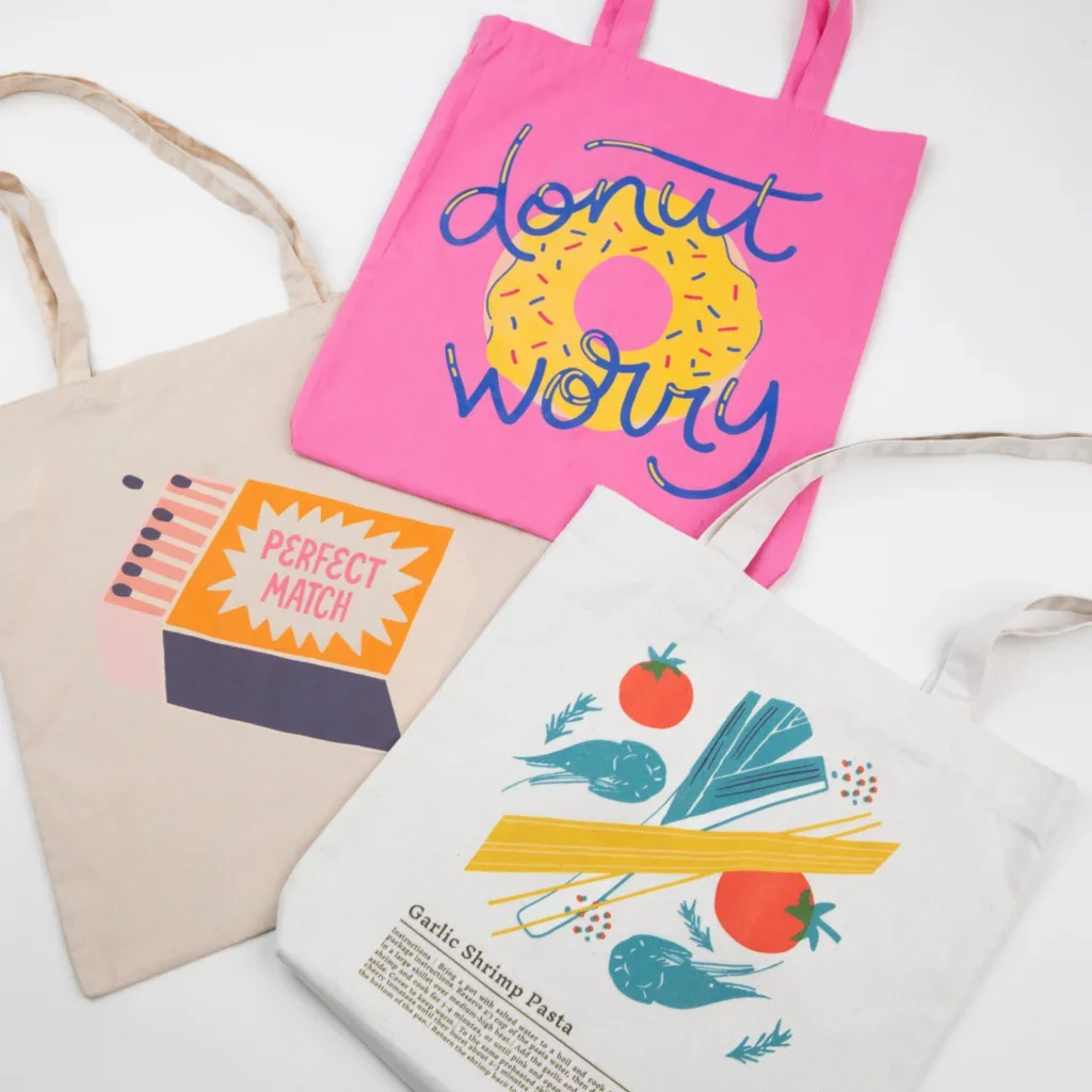 Three custom tote bags with different illustrated prints.