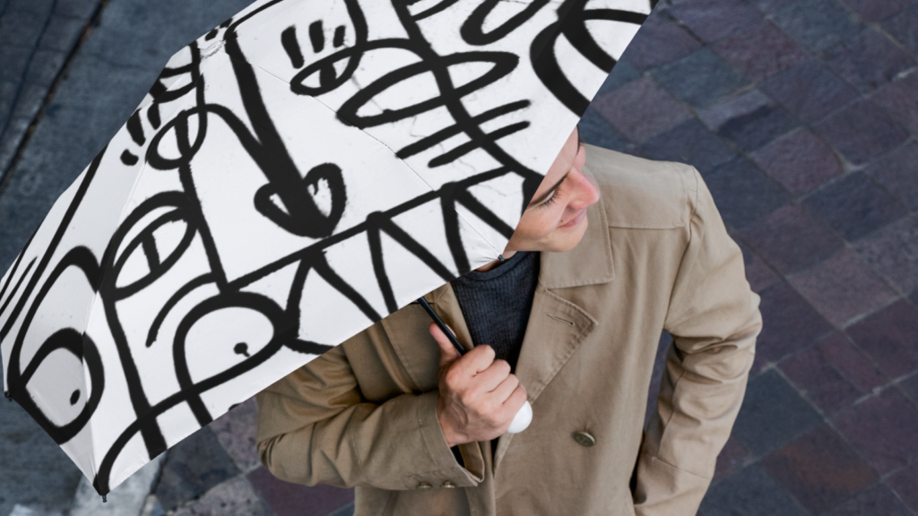 A man standing under a custom white umbrella with a black graffiti-like print.