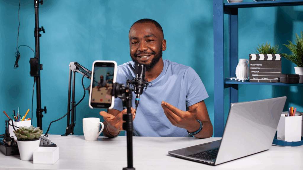 A man recording a podcast and filming it using a mobile phone.