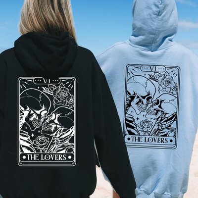 A couple wearing matching hoodies with the Tarot Lovers card design.