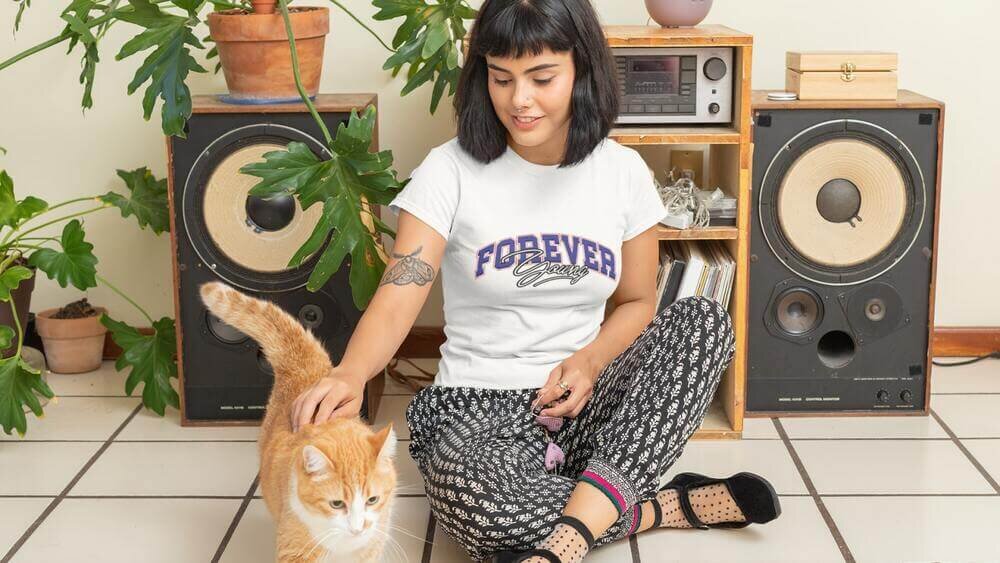 A woman petting a cat in a white Fruit of the Loom 614320 t-shirt with a custom print.