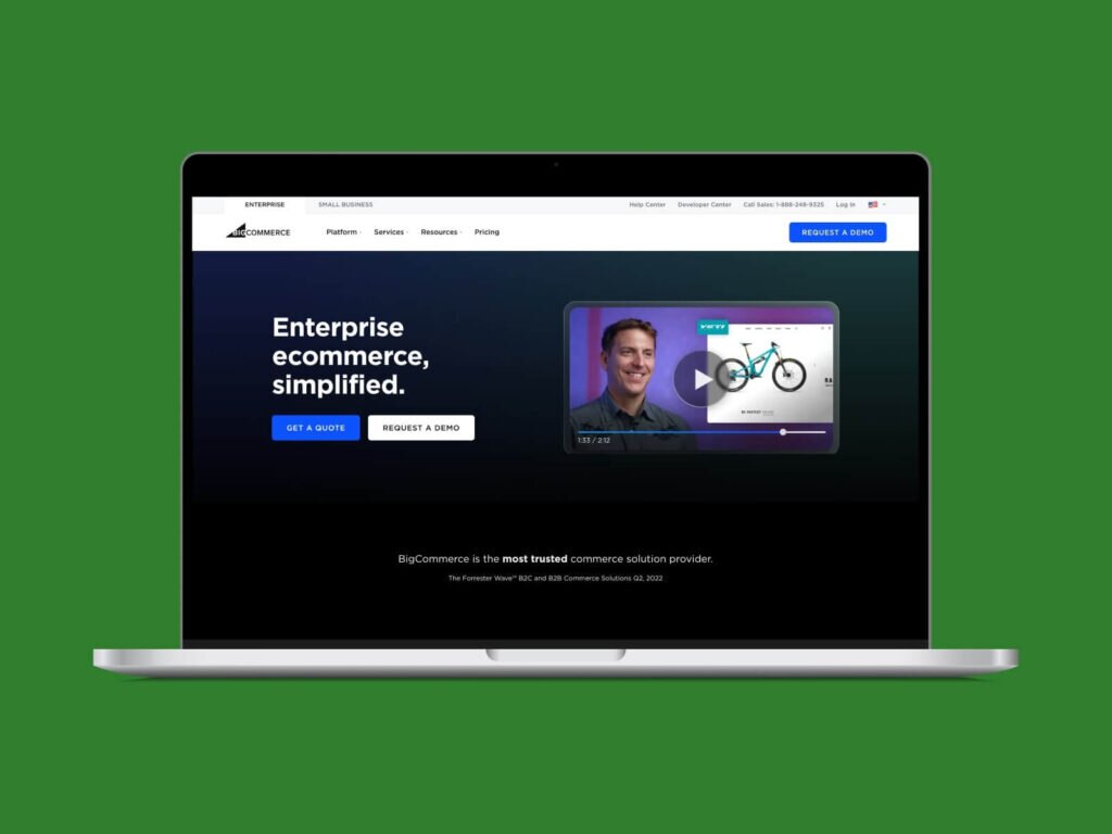 A screenshot of the BigCommerce homepage hero section on a laptop screen with a green background.