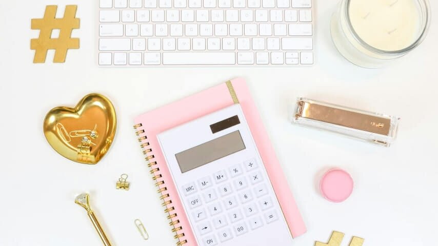 A calculator on top of a pink notebook.