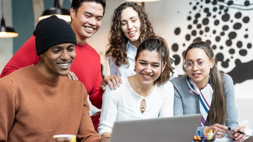 A group of young professionals brainstorming about a marketing plan in front of a laptop.