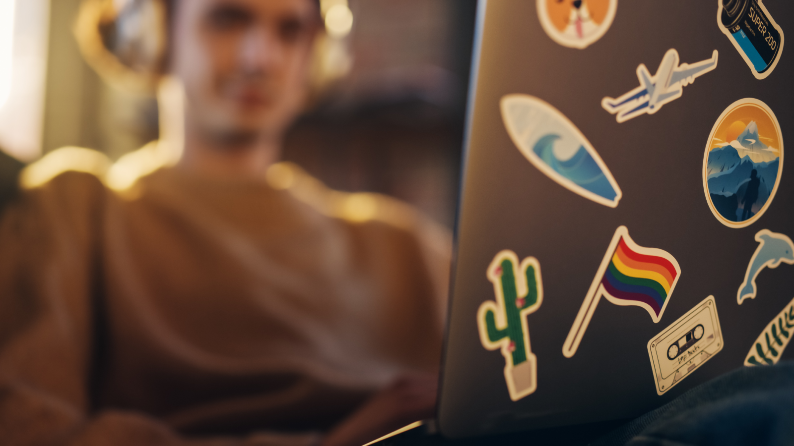 A close-up shot of a laptop with a blurred man in the background.