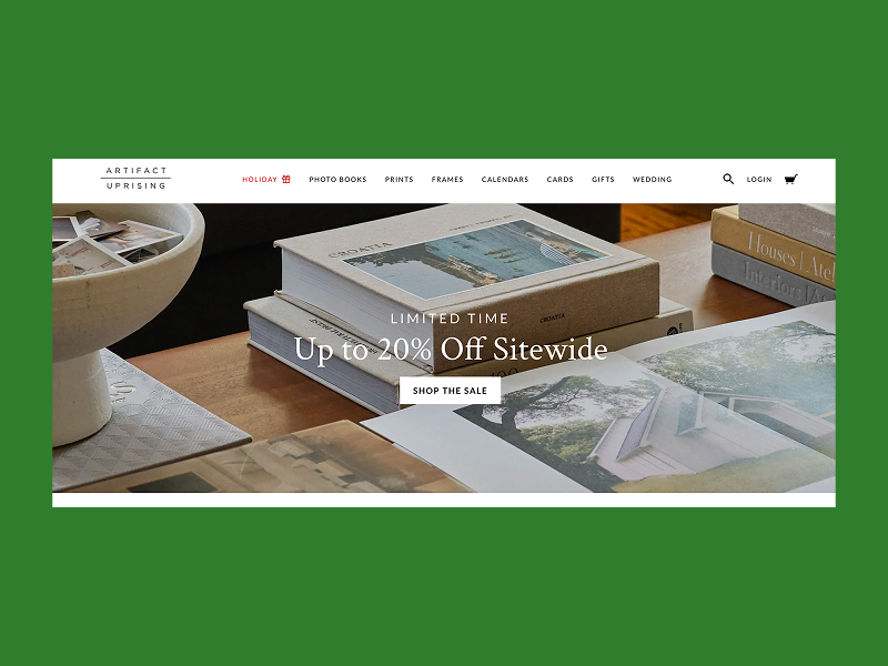 Artifact Uprising homepage showing linen photo books on a table.