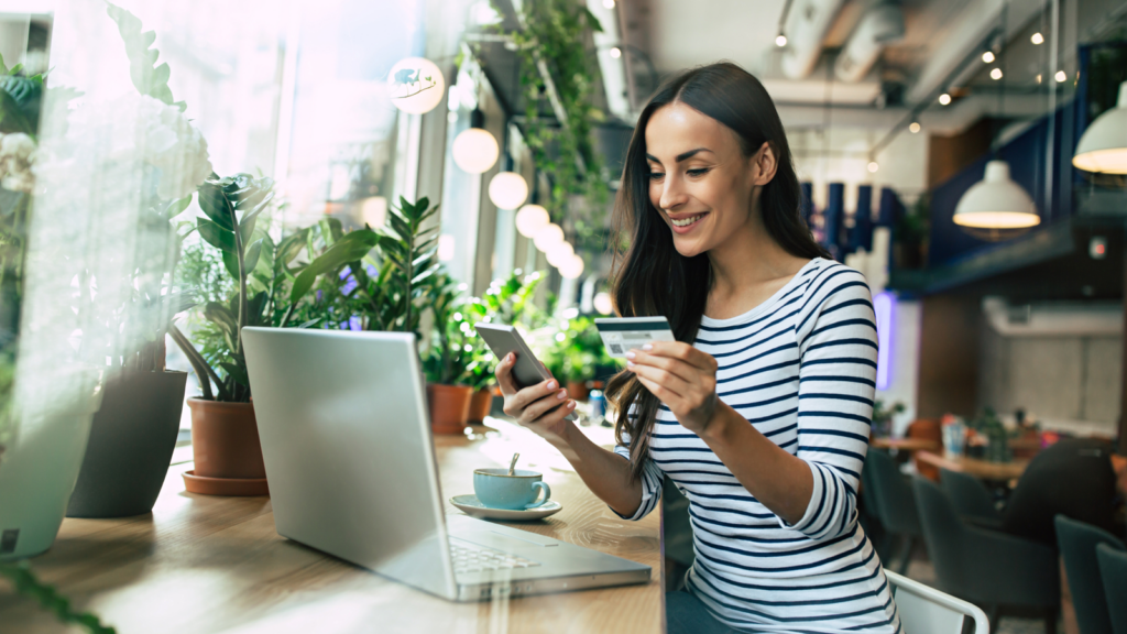 A woman holding a credit card, focused on her laptop screen while making an online payment.