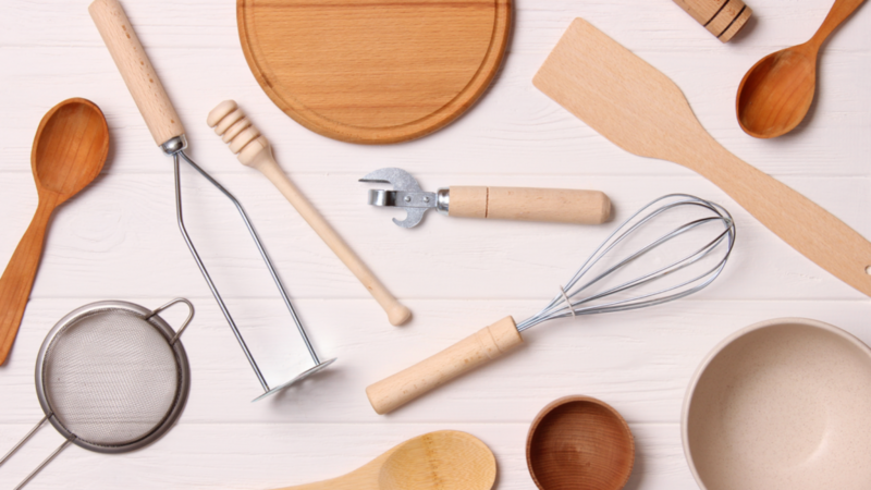 Multiple kitchenware instruments on a wooden background.