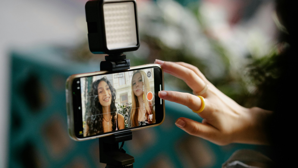 Two young women recording themselves using the front camera of a mobile phone.