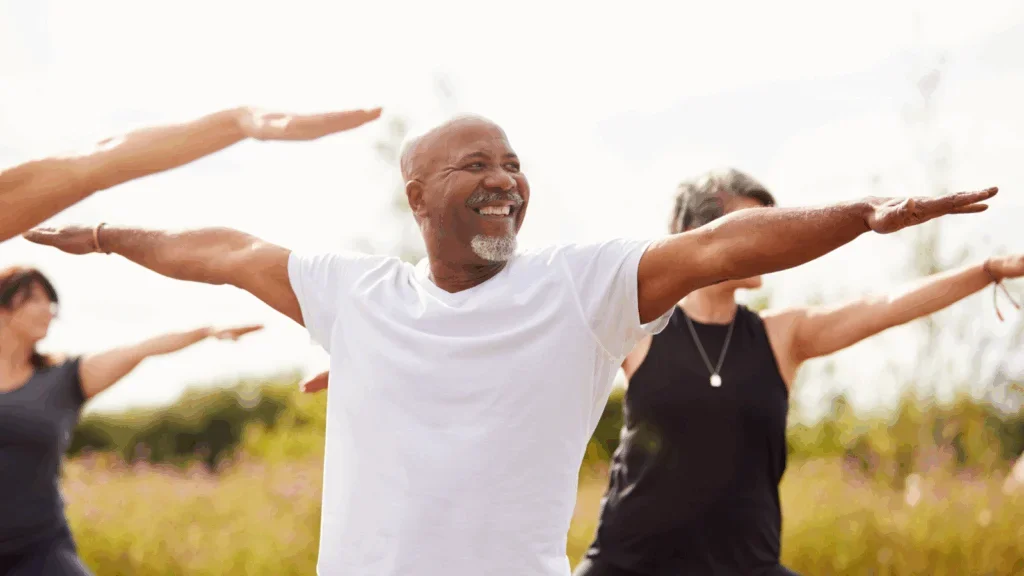 A smiling man in a white t-shirt performing health exercises.