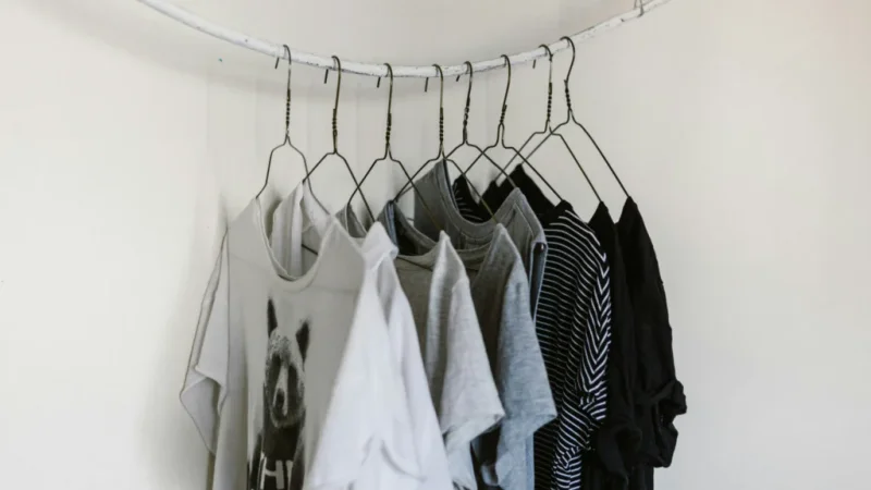 A white wall displaying various clothes neatly hung on hangers.