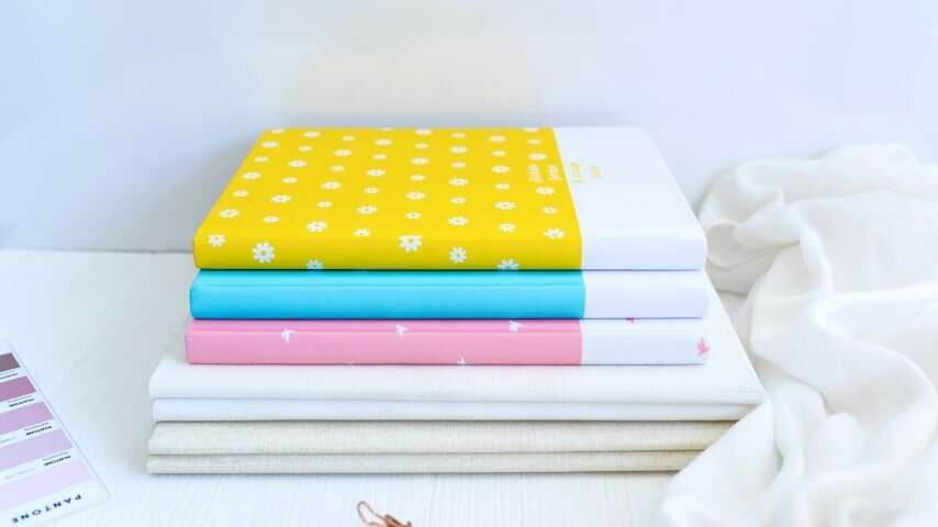 A stack of custom notebooks with different designs lying on a table.