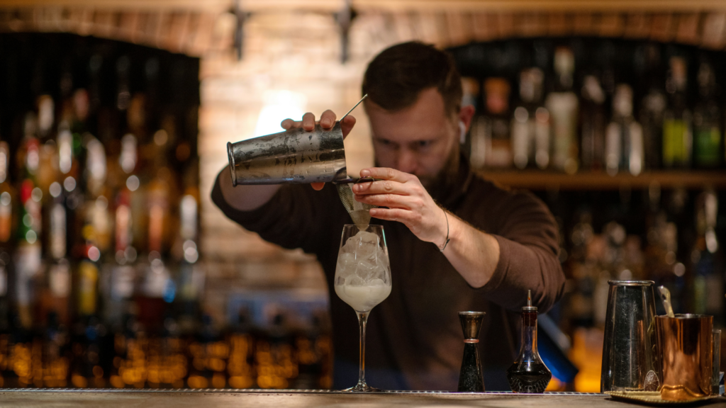 A bartender preparing a cocktail in a wine glass.