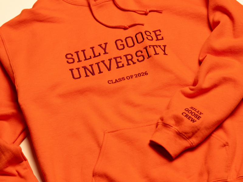 An orange sweatshirt with "SILLY GOOSE UNIVERSITY CLASS OF 2026" printed on the front and "SILLY GOOSE CREW" on one sleeve.