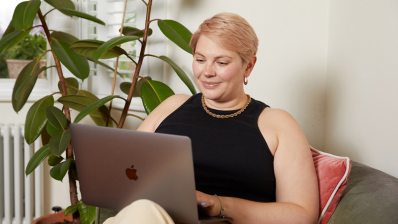 A young woman with short hair sits in a chair with a laptop, checking different TikTok metrics.