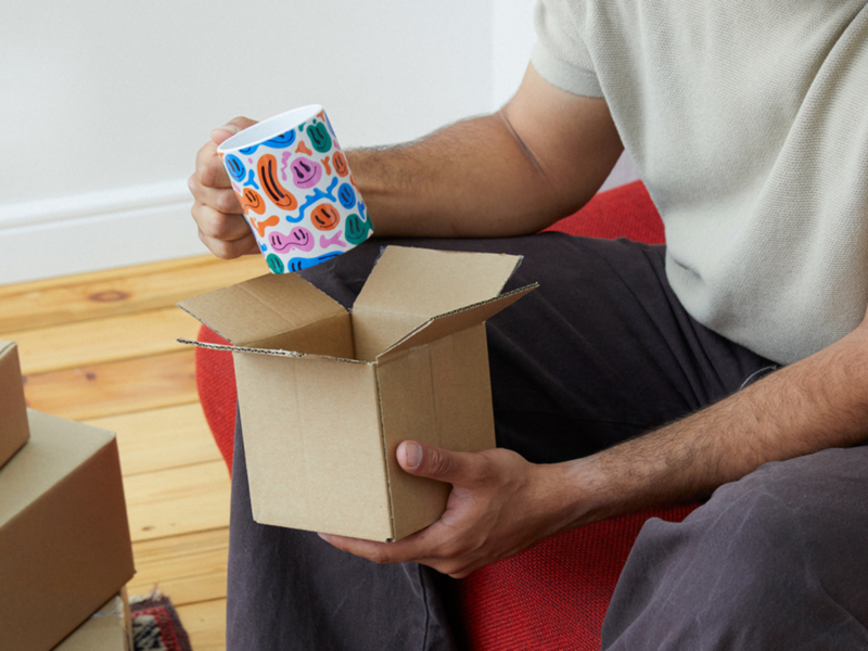 A man relaxes on a couch, cradling a new coffee mug.