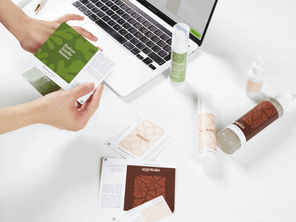 Multiple beauty products on top of a table, next to a laptop.