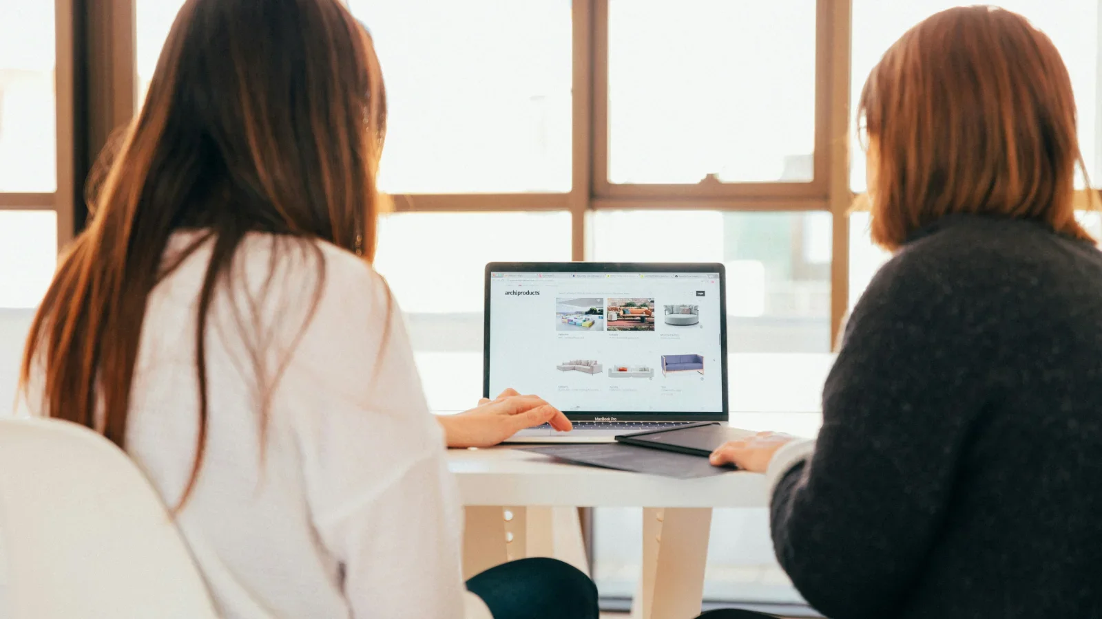 Two women sitting in front of a laptop and searching for information.