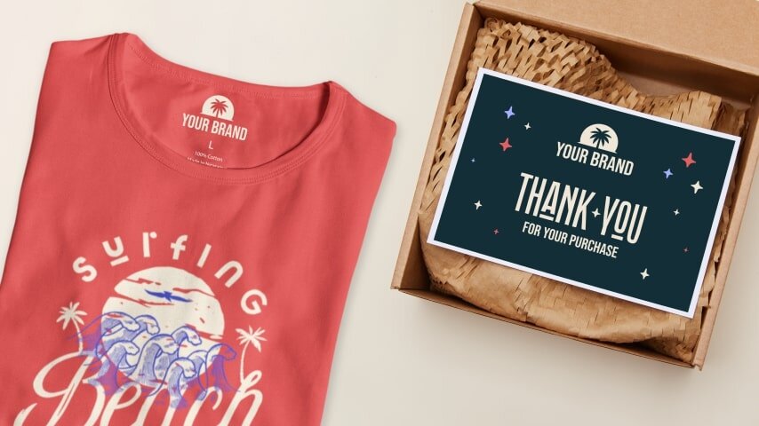 Folded orange tee with a visible neck label print next to a package with a dark green “Thank you for your purchase” card on top.