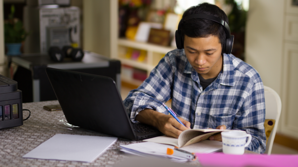 A man with headphones focused on his laptop, engaged in work or a task.
