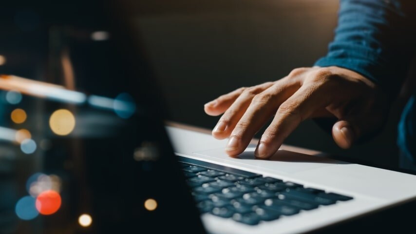 A man's hand on a laptop touchpad.