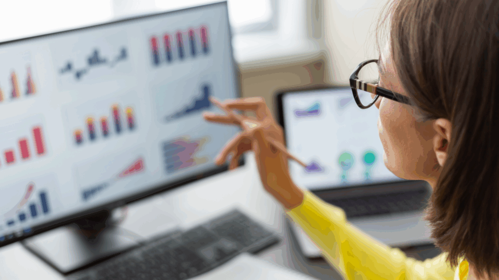 A woman analyzes graphs displayed on a computer screen, focusing intently on the data presented.
