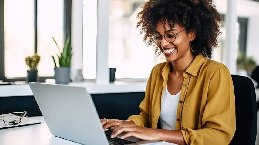 A smiling woman working on her laptop.