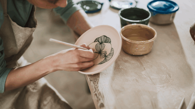 A woman painting a handmade plate.