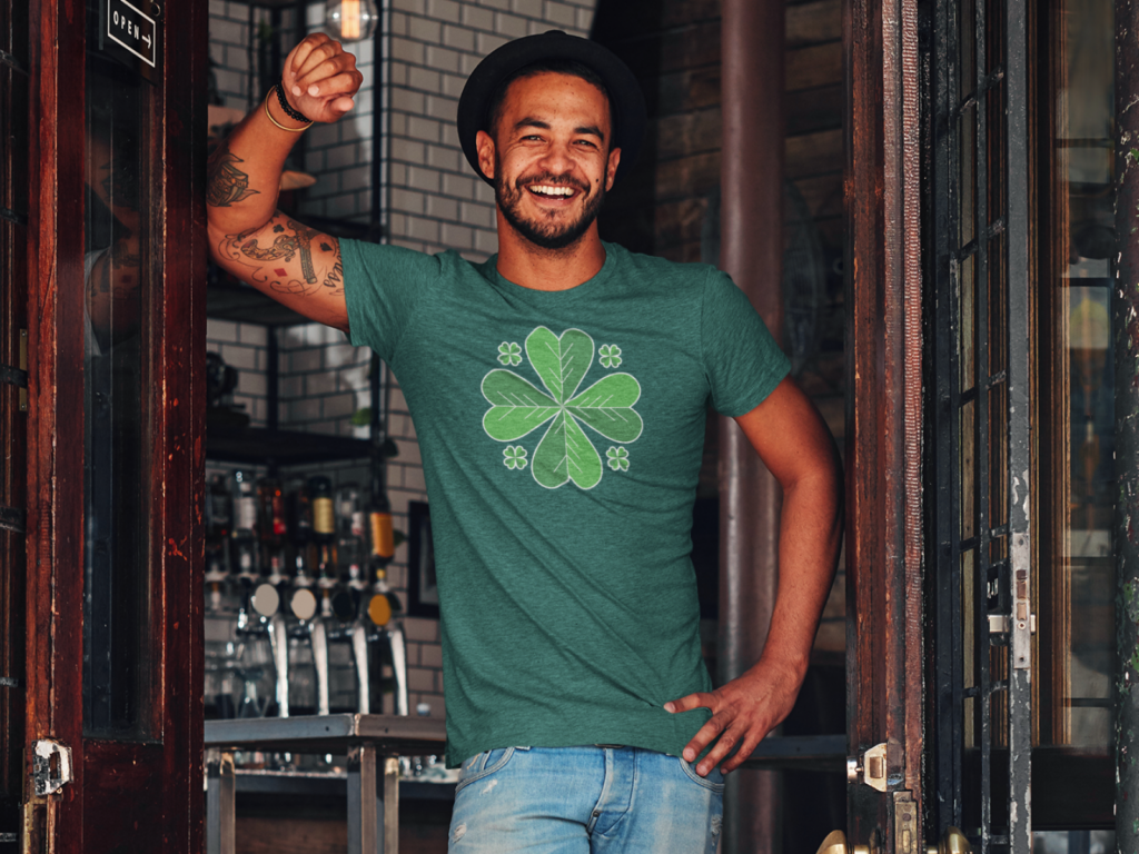 A man in a green shirt featuring a shamrock, smiling and enjoying a festive atmosphere.