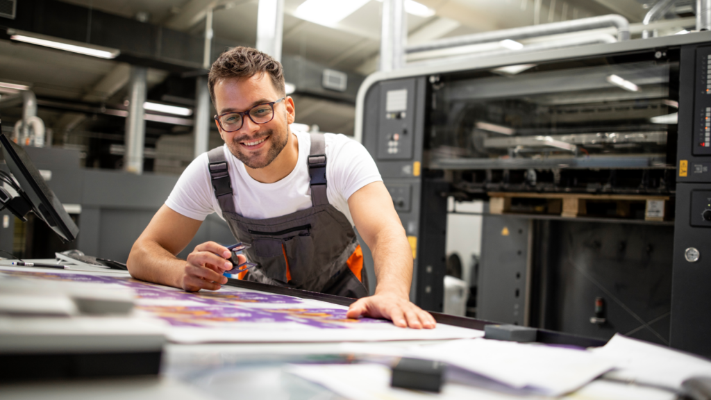 A smiling man working on an industrial printer.
