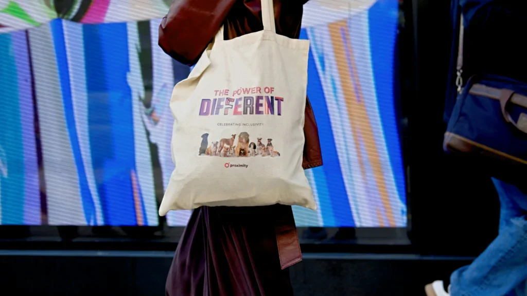 A woman strolls along the street, carrying a tote bag, surrounded by urban scenery.