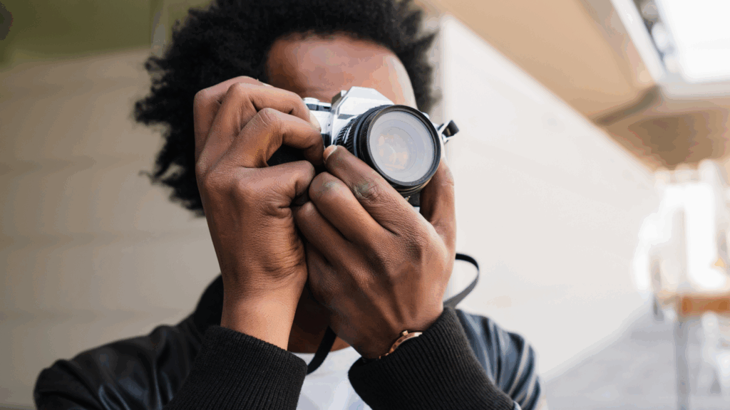 A man is capturing an image with a camera, focused on his subject in an outdoor setting.